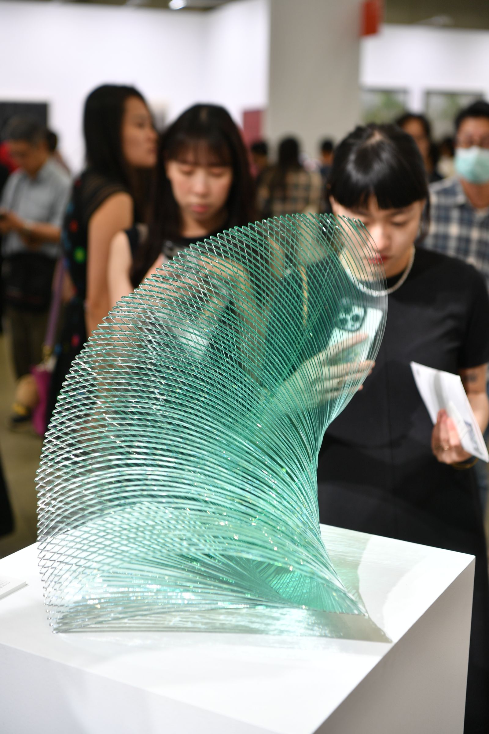 台北藝術展中觀眾觀看綠色玻璃雕塑